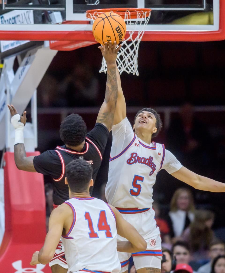 Bradley's Christian Davis (5) blocks a shot by SIU-Edwardsville's Damarco Minor in the second half of their nonconference basketball game Thursday, Dec. 21, 2023 at Carver Arena. The Braves defeated the Cougars 75-64.