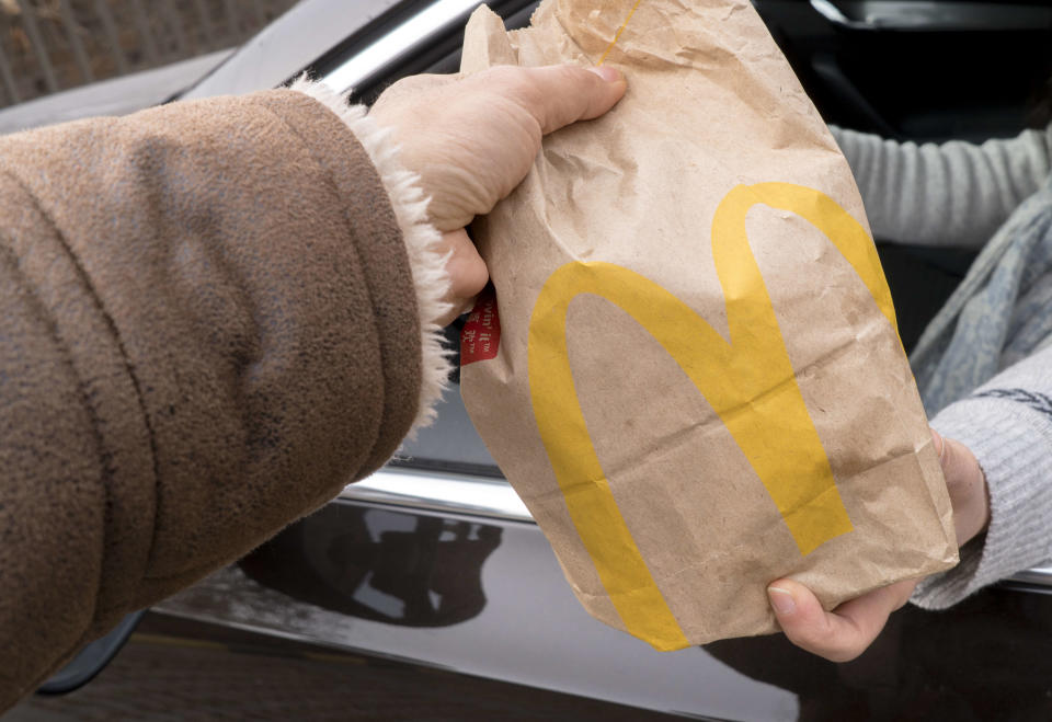 A person receives a bag of McDonald's in their car.