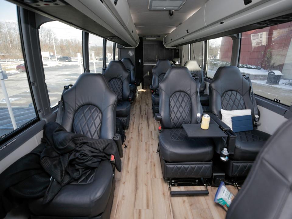 Rows of black leather seats, some topped with jackets, bags, pillows.