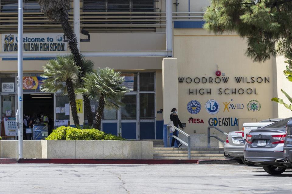 The exterior of a cream-colored school building with the words Woodrow Wilson High School on a wall