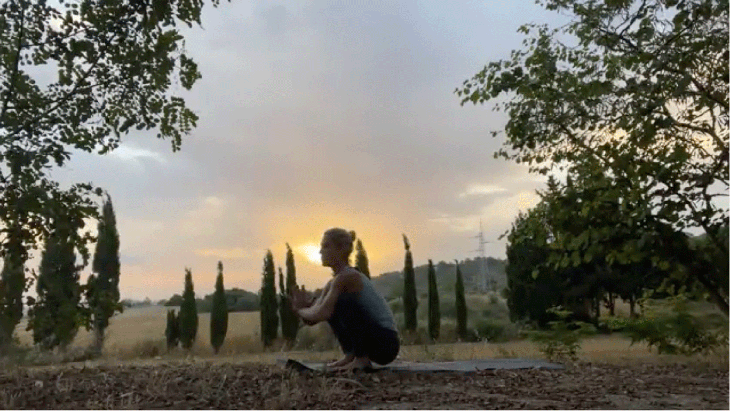 Woman practicing early morning yoga outside in a squat
