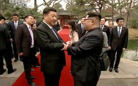 North Korean leader Kim Jong Un, right, and Chinese counterpart Xi Jinping, left, shake hands at Diaoyutai State Guesthouse in Beijing - Credit: AP