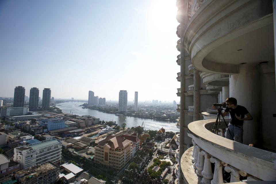 A visitor takes photograghs on a balcony of an abandoned building in Bangkok. The abandoned building, known as Sathorn Unique, dubbed the 'ghost tower' was destined to become one of Bangkok's most luxurious residential addresses but construction was never completed as the Thai economy was hit during the 1997 Asian Financial Crisis. Now, many travellers visit and explore the 49-story skyscraper. (REUTERS/Athit Perawongmetha)