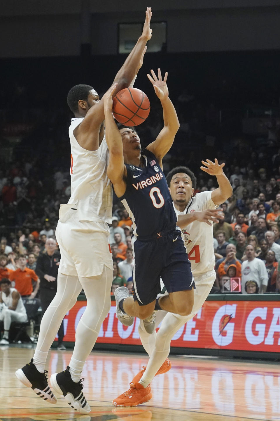 Miami forward A.J. Casey (0) and Nijel Pack (24) defends Virginia guard Kihei Clark (0) during the second half of an NCAA college basketball game, Tuesday, Dec. 20, 2022, in Coral Gables, Fla. (AP Photo/Marta Lavandier)