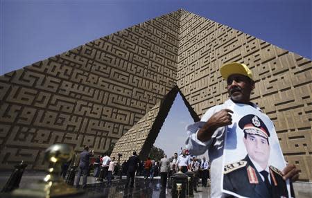 A man holds a poster Army Chief Sisi at the tomb of late Egyptian President Sadat, in Cairo