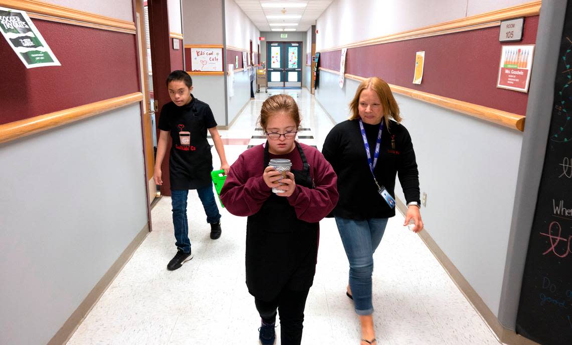 Kate Buerer carefully carries a latte as she and partner Hans Cagabcob and paraeducator Meagan Crum they make a delivery from the Cool Kids Cafe at Goodman Middle School in Gig Harbor, Washington, on Thursday, Sept. 15, 2022.