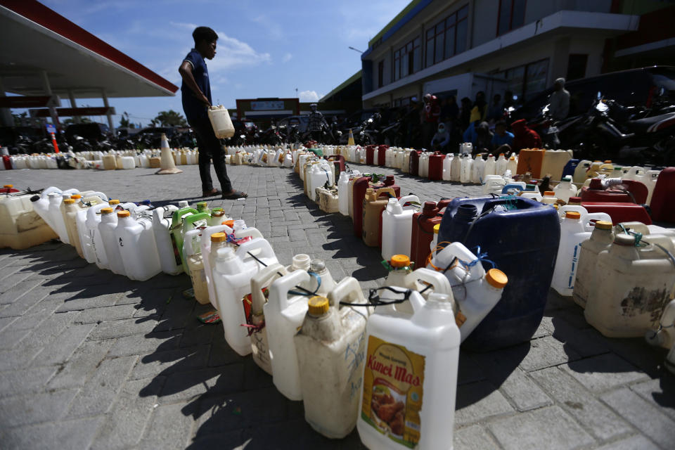 In this Friday, Oct. 5, 2018, file photo, a man looks at lines of jerry cans as people queue up for fuel at a gas station in the earthquake and tsunami-affected city of Palu, Central Sulawesi, Indonesia. (AP Photo/Dita Alangkara, File)