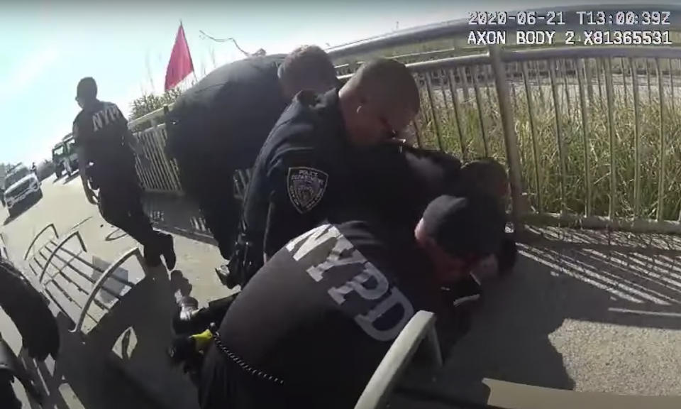 In this photo taken from police body cam video, New York Police officers arrest a man on a boardwalk Sunday, June 21, 2020, in New York. The NYPD says officer David Afanador was arrested Thursday on charges of strangulation and attempted strangulation over the incident last weekend on the Rockaway Beach boardwalk. Video showed Afanador with his arm wrapped around a man’s neck for several seconds during an arrest. (NYPD via AP)