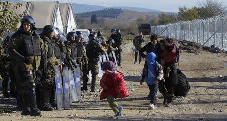 Migrants walks past Macedonian police after crossing the Macedonian-Greek border, near Gevgelija, Macedonia, November 30, 2015. REUTERS/Ognen Teofilovski