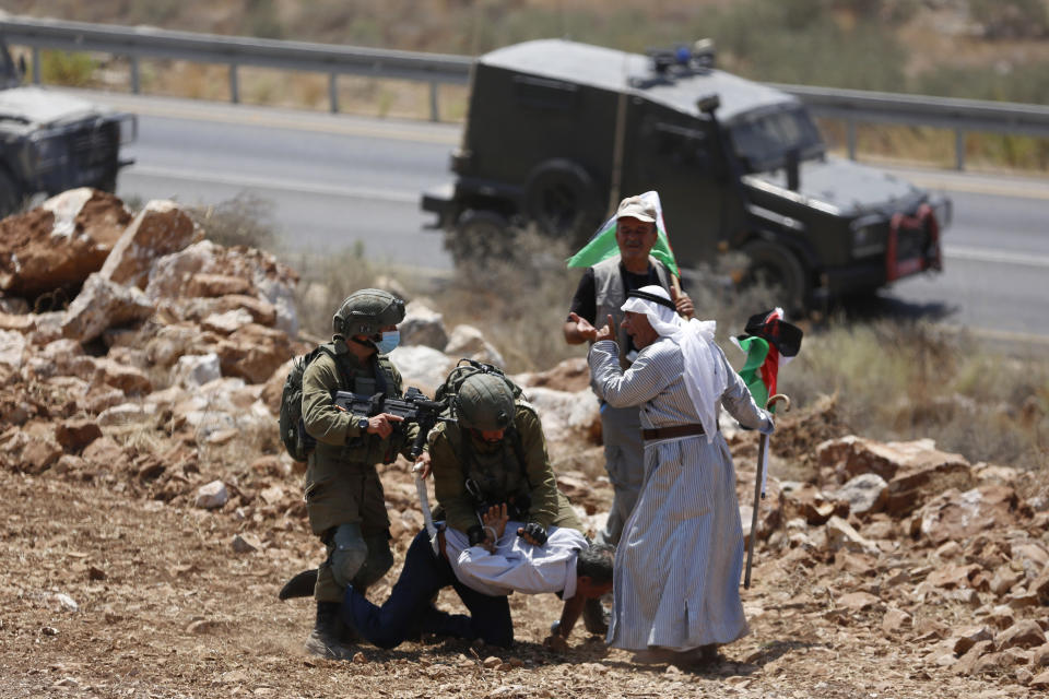 Israeli soldiers detain a Palestinian man during a protest against the to expand Israeli settlements in the village of Khirbet Jubara near the West Bank city of Tulkarm, Thursday, Aug. 20, 2020. (AP Photo/Majdi Mohammed)