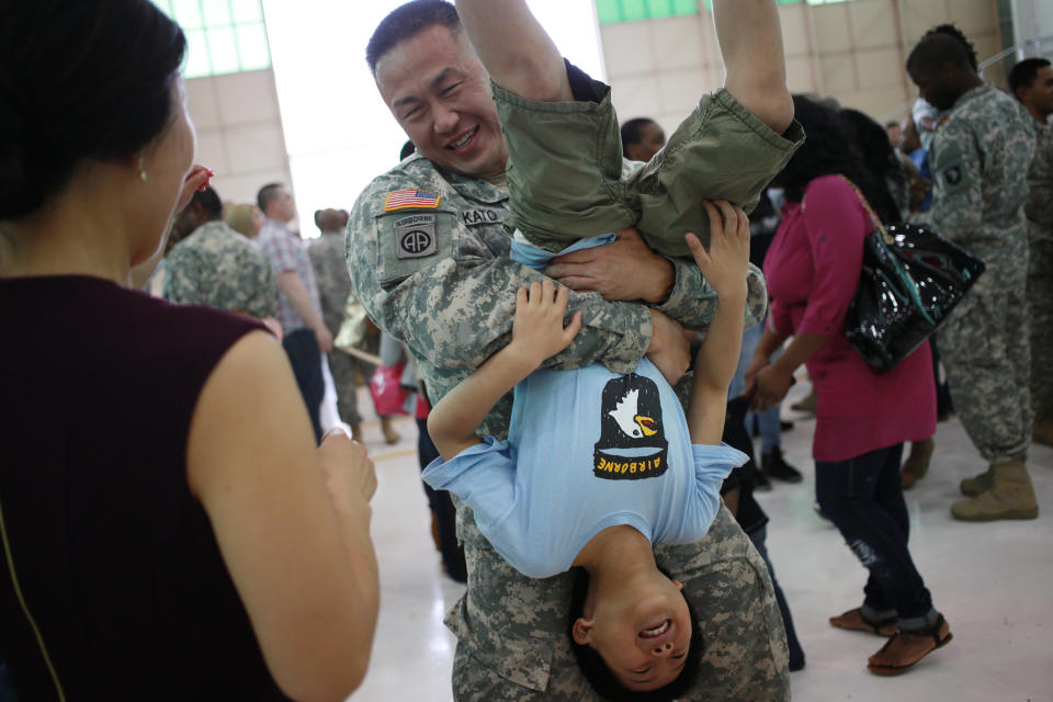 Lt. Col. Sung Kato of the U.S. Army's 101st Airborne Division gives his son an upside-down hug during a homecoming ceremony at Campbell Army Airfield on March 21, 2015, in Fort Campbell, Kentucky.