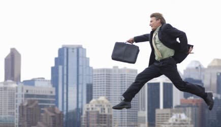 Businessman jumping over city