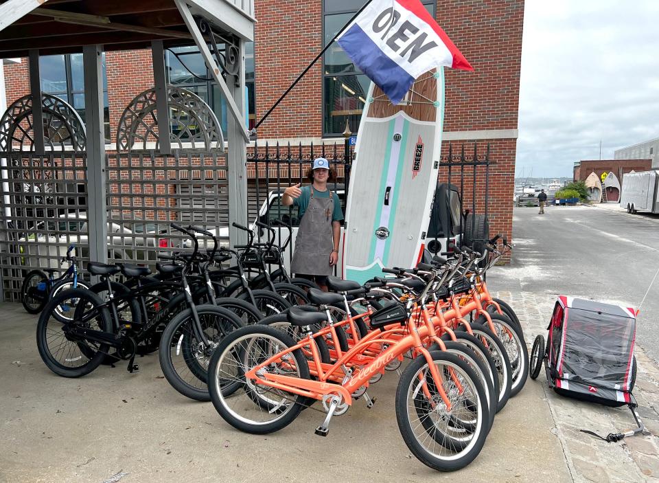 Shop manager Nixon Brownell stands next to some of the electric bikes that can be rented from Island Adventures, located at 4 Spring Wharf in Newport.