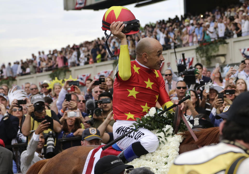 FILE - Jockey Mike Smith tips his helmet to the crowd as he rides Justify to the winner's circle after winning the 150th running of the Belmont Stakes horse race and Triple Crown on June 9, 2018, in Elmont, N.Y. Earlier in 2023, horse racing was rocked by the deaths less than six weeks apart of two young jockeys, 23-year-old Avery Whisman and 29-year-old Alex Canchari, each of whom killed himself. A friend of Whisman's, Triple Crown-winning rider Mike Smith has over three decades seen similar tragedies unfold. (AP Photo/Peter Morgan, File)