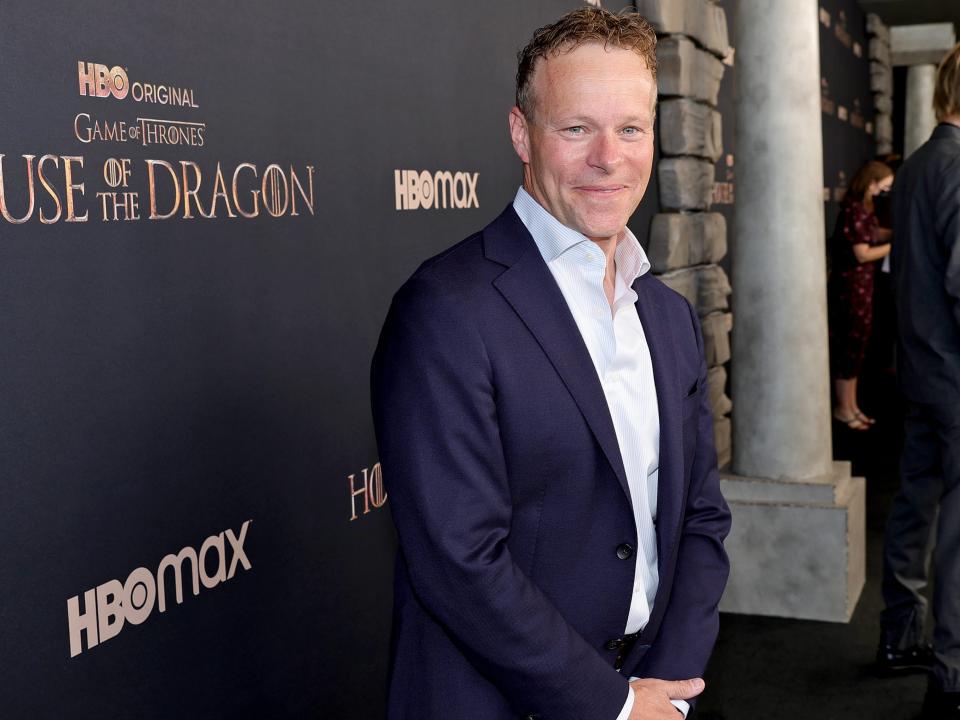 Chris Licht in a white shirt and blue blazer in front of an HBO backdrop with "House of the Dragon" on it.