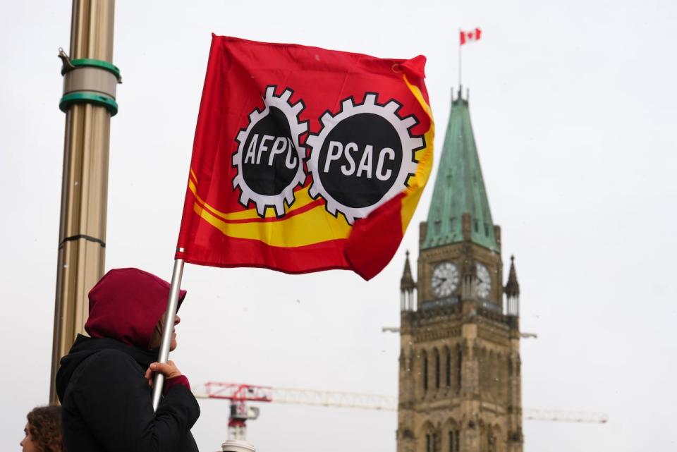 A Public Service Alliance of Canada (PSAC) worker holds a flag on a picket line near Parliament Hill in Ottawa on April 19, 2023.
