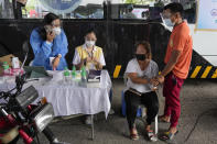 A woman holds the hands of her husband as they wait to be inoculated with China's Sinovac COVID-19 vaccine at a drive-thru vaccination center in Manila, Philippines, Tuesday, June 22, 2021. The Philippine president has threatened to order the arrest of Filipinos who refuse COVID-19 vaccination and told them to leave the country for hard-hit countries like India and the United States if they would not cooperate with massive efforts to end the pandemic. (AP Photo/Aaron Favila)