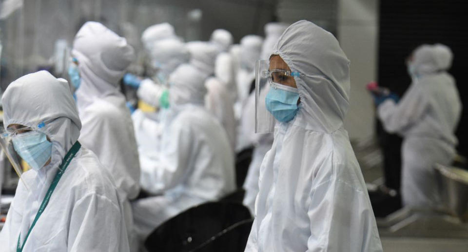 Airline ground staff wearing protective gear work at the counter at the airport in Manila on August 4, 2020.