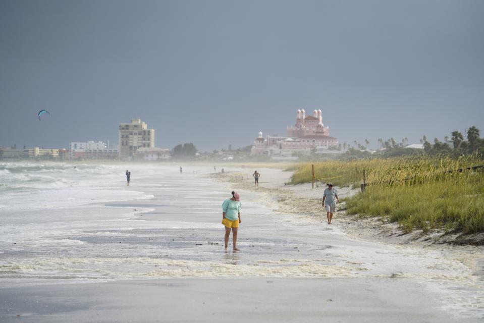 Beach walkers walk along the sand on Pass-a-Grille the morning after Tropical Storm Elsa moved over the Tampa Bay Area, Wednesday, July 7, 2021 in St. Pete Beach, Fla. (Martha Asencio-Rhine/Tampa Bay Times via AP)