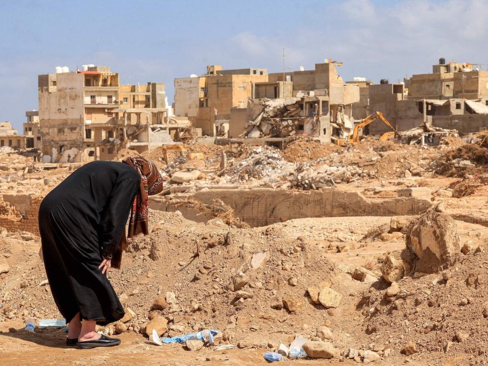 A survivor prays over the rubble of her destroyed house in Derna.