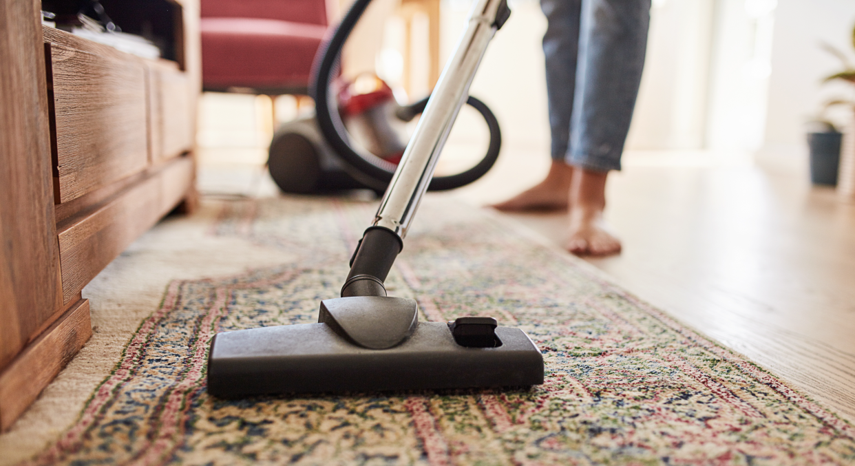 Woman vacuuming rug at home.