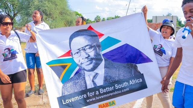 Supporters of Lovemore Ndou display a poster with the message 'Lovemore for a Better South Africa' while wearing branded T-shirts 