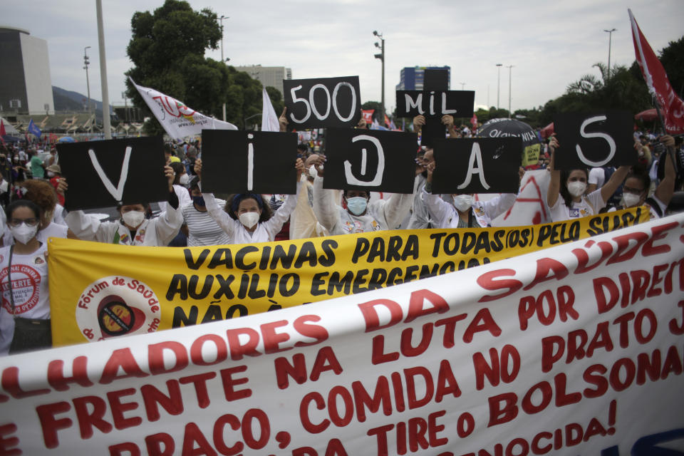 Women simultaneously hold up placards with a message that reads in Portuguese; "500K deaths! His fault!" during a demonstration against Brazilian President Jair Bolsonaro's handling of the coronavirus pandemic and economic policies protesters say harm the interests of the poor and working class, in Rio de Janeiro, Brazil, Saturday, June 19, 2021. Brazil is approaching an official COVID-19 death toll of 500,000 — second-highest in the world. (AP Photo/Bruna Prado)