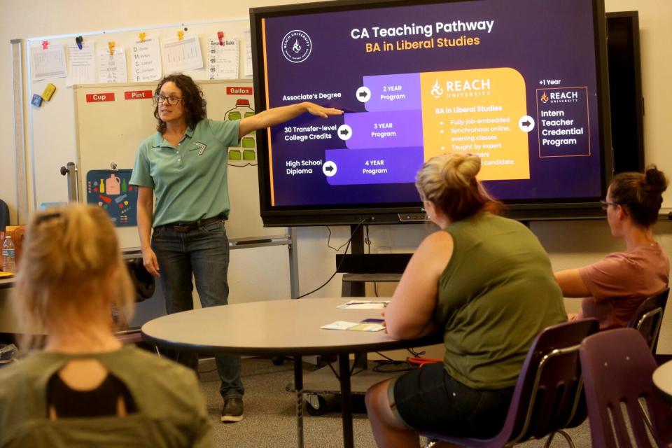 A woman stands before a screen as leads a workshop on helping people interested in obtaining teaching credentials