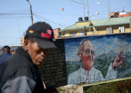 A man is seen next to a damaged mural of Pope Francis in El Alto, on the outskirts of La Paz, July 7, 2015, ahead of Pope Francis' visit to Ecuador, Bolivia and Paraguay in his Latin-American tour. REUTERS/Carlos Sanchez Navas