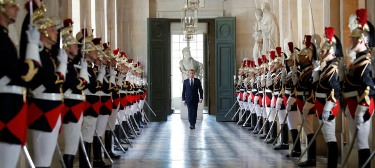 French President Emmanuel Macron walks past an honour guard as he prepares to address a special session of both houses of parliament at the opulent Versailles palace outside Paris