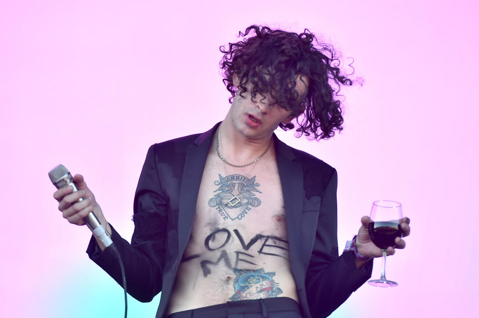 Matty holding a microphone and a wine glass