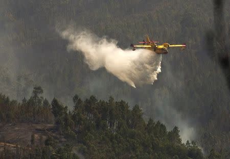 A firefighting plane dumps water on a forest fire in Alto da Louriceira, Portugal, June 21, 2017. REUTERS/Miguel Vidal