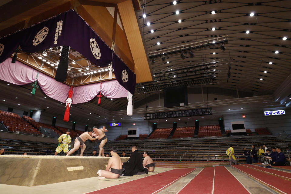 Sumo wrestlers fight on the ring as spectators' seats are empty during the Spring Grand Sumo Tournament in Osaka, western Japan, Sunday, March 8, 2020. The 15-day sumo tournament started on Sunday with no spectators, affected by fears of the new coronavirus outbreak. (Kyodo News via AP)