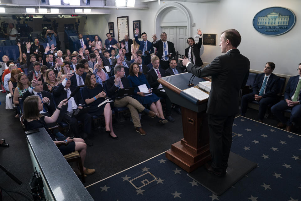 FILE - In this June 7, 2021 photo, journalists raise their hands to ask a question as White House national security adviser Jake Sullivan speaks during a press briefing at the White House in Washington. Reporters traveling to the United Kingdom ahead of President Joe Biden’s first overseas trip were delayed seven hours late Tuesday after their chartered plane was overrun by cicadas.The Washington, D.C. area is among the many parts of the country suffering under the swarm of Brood X, a large emergence of the loud 17-year insects that take to dive-bombing onto moving vehicles and unsuspecting passersby. Weather and crew rest issues also contributed to the flight delay. (AP Photo/Evan Vucci)