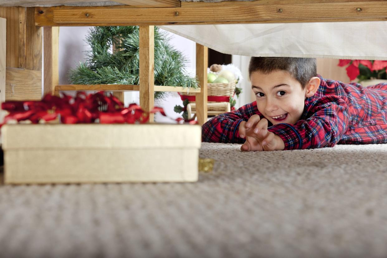 A young elementary boy delighted at seeing a boxed gift under his parents' bed.