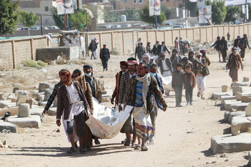 FILE PHOTO: Relatives carry bodies of the victims of air strikes on a detention center to be buried at a cemetery, in Saada