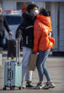 Travelers wearing face masks embrace outside the Beijing Railway Station in Beijing, Saturday, Feb. 15, 2020. People returning to Beijing will now have to isolate themselves either at home or in a concentrated area for medical observation, said a notice from the Chinese capital's prevention and control work group published by state media late Friday. (AP Photo/Mark Schiefelbein)