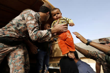 A Jordanian soldier carries a Syrian refugee child to help him board a Jordanian army vehicle with his family after they crossed into Jordanian territory, in Al Ruqban border area, near the northeastern Jordanian border with Syria, and Iraq, near the town of Ruwaished, 240 km (149 miles) east of Amman September 10, 2015. REUTERS/Muhammad Hamed/Files