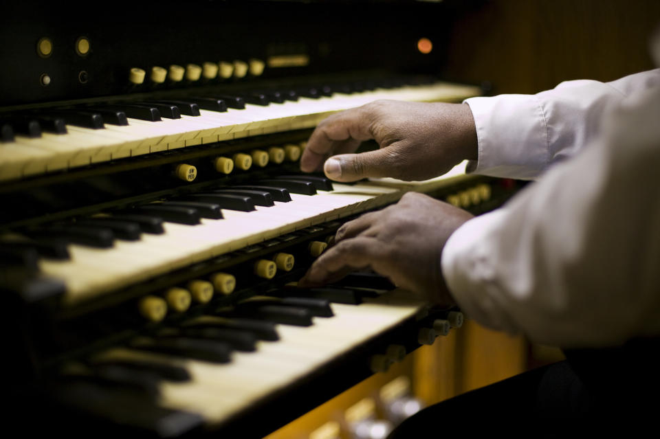 Close-up of a person's hands playing an organ keyboard