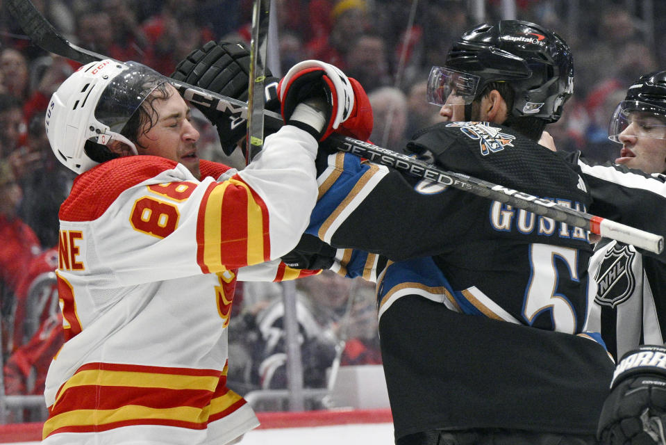 Washington Capitals defenseman Erik Gustafsson, right, scuffles with Calgary Flames left wing Andrew Mangiapane (88) during the second period of an NHL hockey game, Friday, Nov. 25, 2022, in Washington. (AP Photo/Nick Wass)