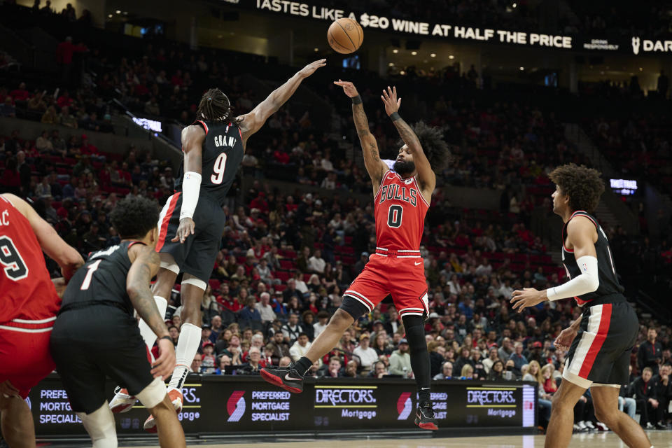 Chicago Bulls guard Coby White, right, shoots a jump shot against Portland Trail Blazers forward Jerami Grant, left, during the first half of an NBA basketball game in Portland, Ore., Sunday, Jan. 28, 2024. (AP Photo/Troy Wayrynen)