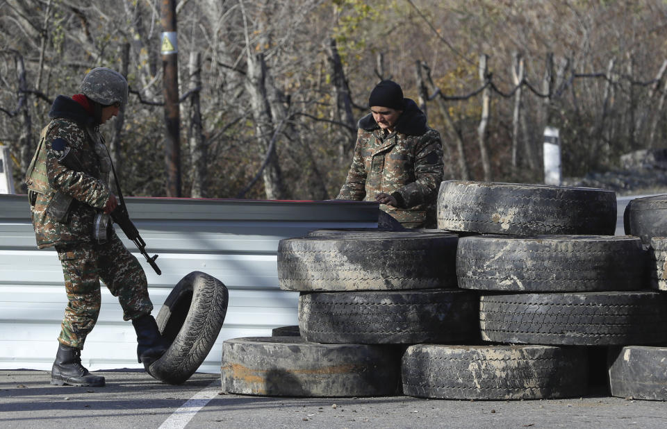 Ethnic Armenian militants stand at a checkpoint near village of Charektar in the separatist region of Nagorno-Karabakh at a new border with Kalbajar district turned over to Azerbaijan, Wednesday, Nov. 25, 2020. The Azerbaijani army has entered the Kalbajar region, one more territory ceded by Armenian forces in a truce that ended deadly fighting over the separatist territory of Nagorno-Karabakh, Azerbaijan's Defense Ministry said Wednesday. The cease-fire, brokered by Russia two weeks ago, stipulated that Armenia hand over control to Azerbaijan of some areas its holds outside Nagorno-Karabakh's borders. (AP Photo/Sergei Grits)