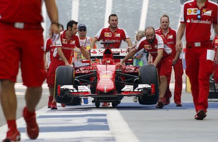 Ferrari Formula One team members push the car of driver Germany's Sebastian Vettel in pit lane before the third practice session of the Singapore F1 Grand Prix at the Marina Bay street circuit September 19, 2015. REUTERS/Edgar Su