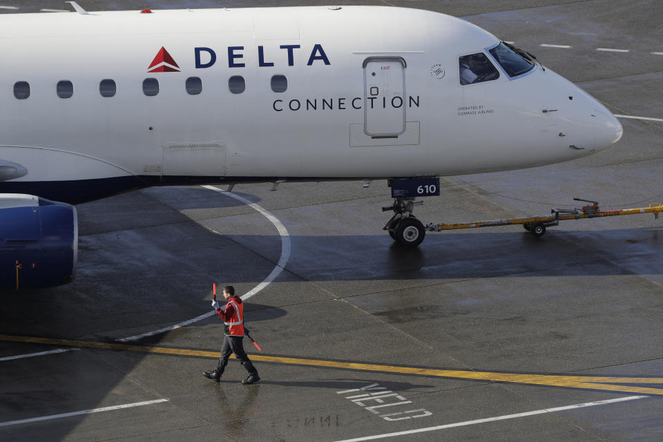 FILE - In this Feb. 5, 2019, file photo a ramp worker guides a Delta Air Lines plane at Seattle-Tacoma International Airport in Seattle. Delta Air Lines reports earns Tuesday, Oct. 8. (AP Photo/Ted S. Warren, File)