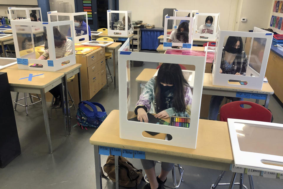 FILE - In this March 2, 2021, file photo, socially distanced, and with protective partitions, students work on an art project during class at the Sinaloa Middle School in Novato, Calif. U.S. guidelines that say students should be kept 6 feet apart in schools are receiving new scrutiny from federal health experts, state governments and education officials working to return as many children as possible to the classroom. (AP Photo/Haven Daley, File)