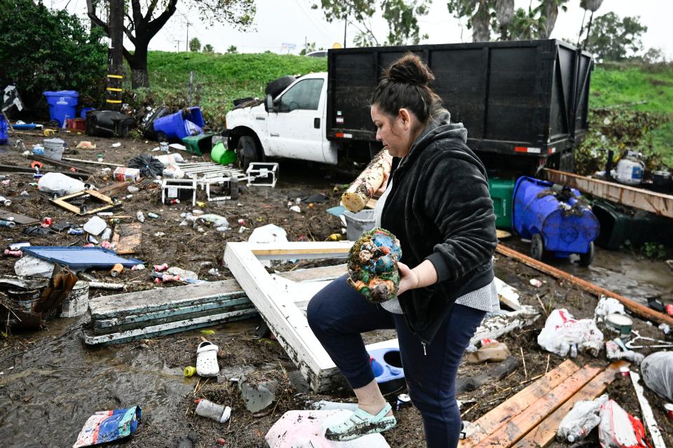 Marlene Sanchez-Barriento salavages items behind her home damaged by flooding, Tuesday, Jan. 23, 2024, in. Sanchez-Barriento's home was damaged when flood waters rushed though her home on Monday, Jan. 23.