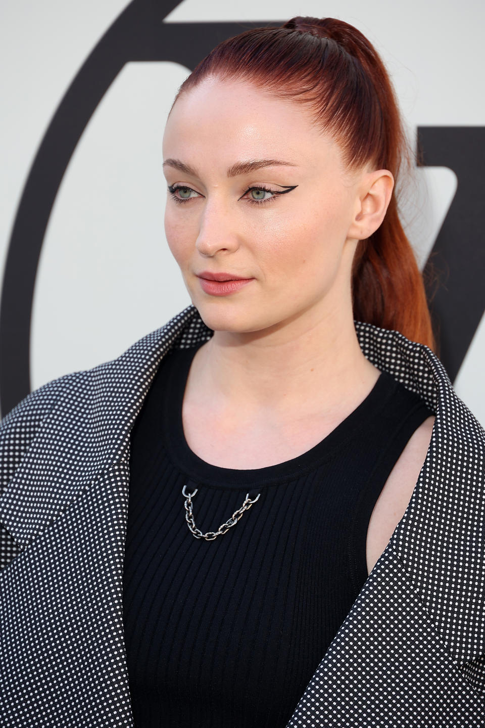 Sophie Turner in a black outfit with a dotted pattern, sporting a ponytail at an event