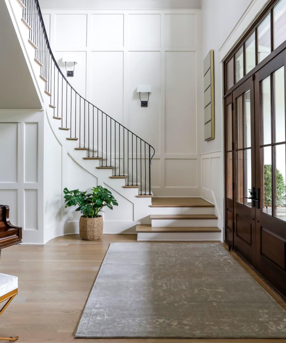 Wooden staircase, white panelled walls, black banister