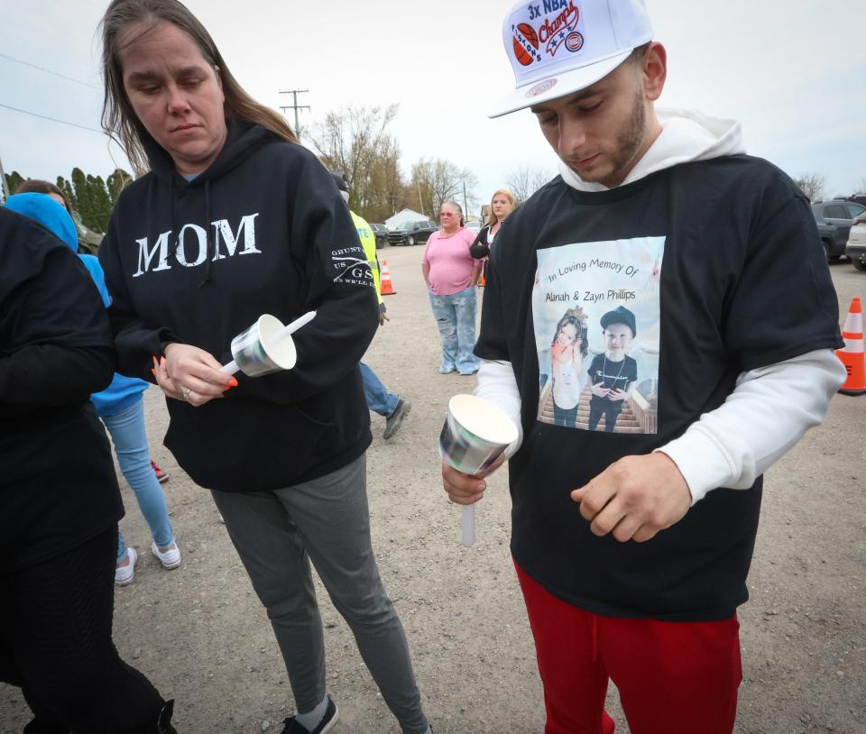 Missy Kowalczyk (links) und Brent Green versuchen, bei einer Mahnwache für Alayna und Zayn Phillips bei der Swan Boat Club-Zeremonie am Freitag, dem 26. April 2024 in Newport, Kerzen anzuzünden.  Die starken Winde vor dem Eriesee verhinderten, dass sich die Kerzen entzündeten.