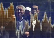 Men are reflected in a screen displaying a graph showing the movements of recent share averages outside a brokerage in Tokyo April 11, 2014. REUTERS/Issei Kato